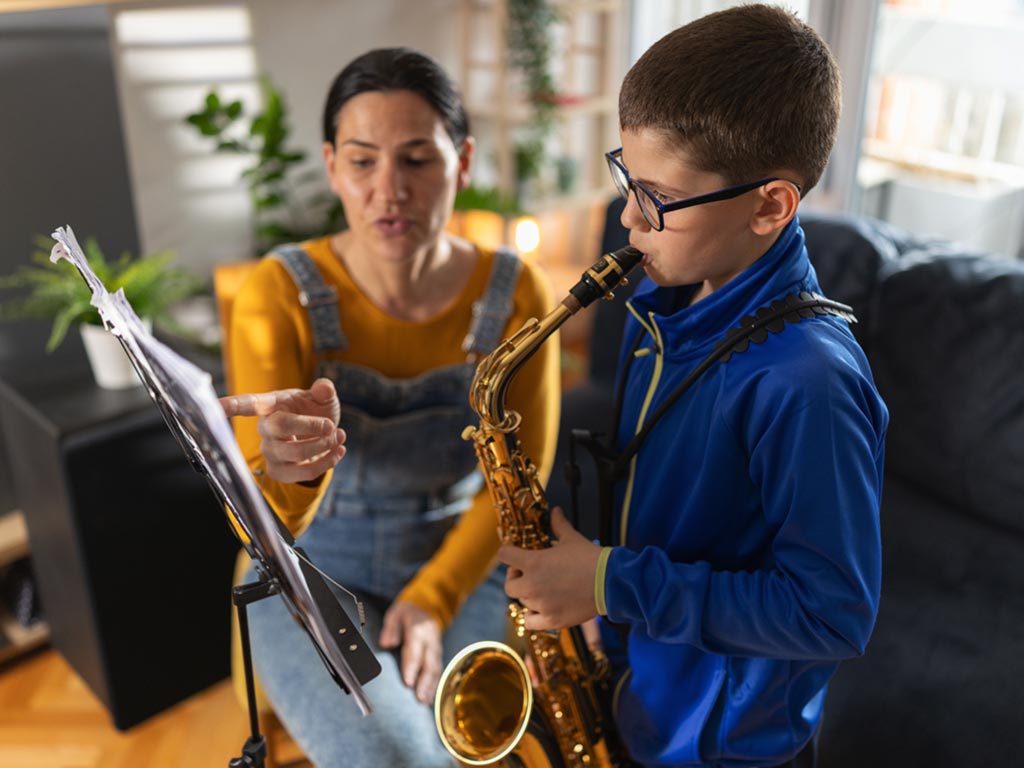 Child learning saxophone with teacher