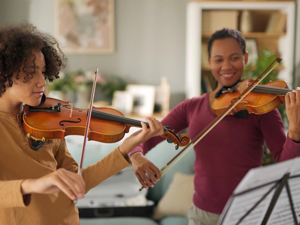 Teen learning violin with teacher